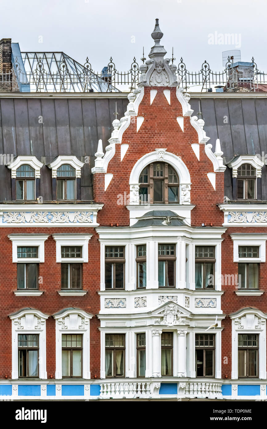 The facade of an old red brick building with white stucco windows and balconies in the old part of Riga. Stock Photo