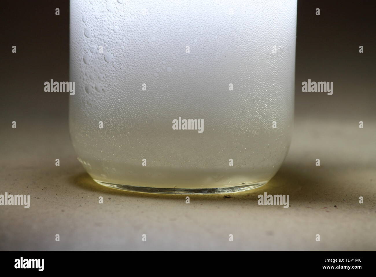 Closeup of a vinegar and baking soda reaction happening in the bottom of a glass jar; creating a