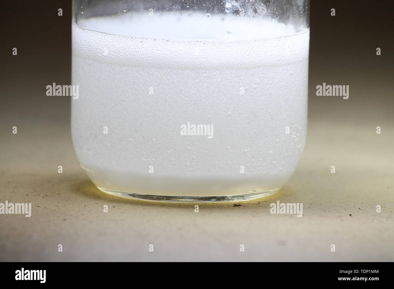 Closeup of a vinegar and baking soda reaction happening in the bottom of a glass jar; creating a