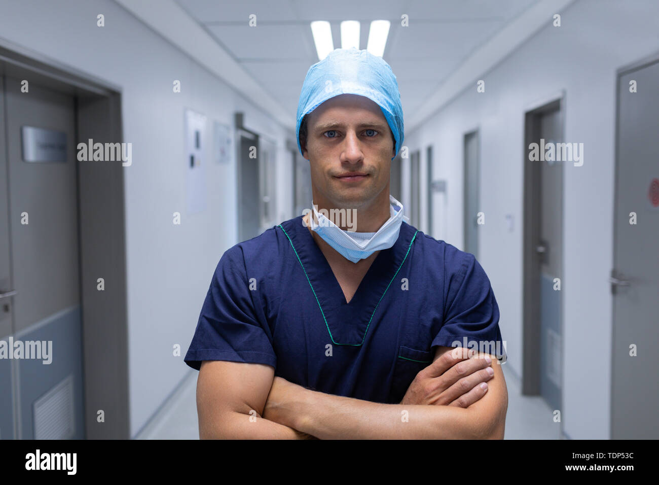 Male surgeon standing with arms crossed in the corridor at hospital ...