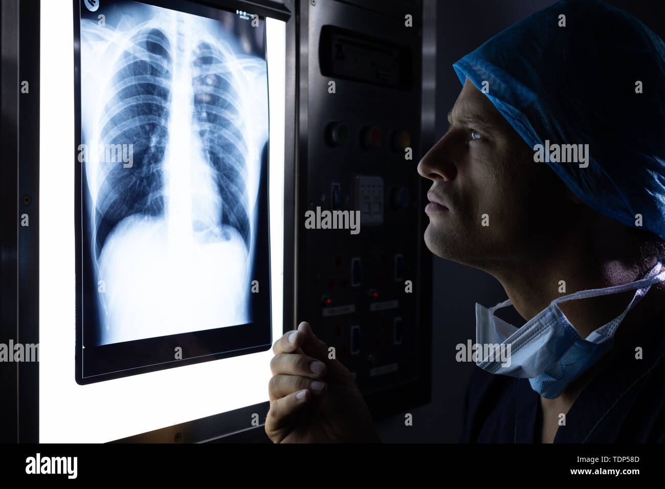 Male surgeon examining xray on light box in operation theater Stock