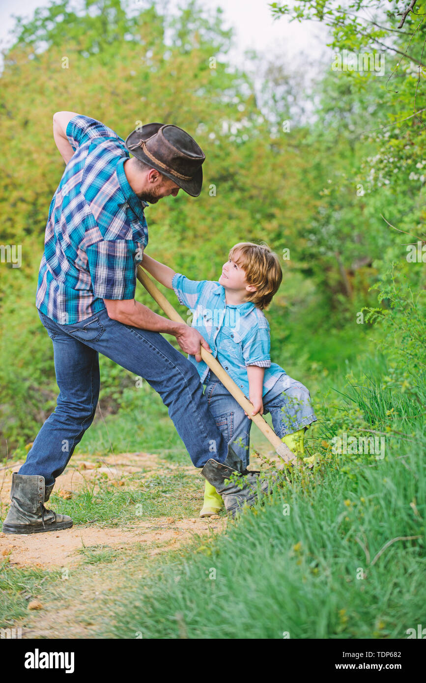 father and son planting family tree. rich natural soil. Eco farm. Ranch.  small boy child help father in farming. new life. soils and fertilizers.  happy earth day. Dig grounf with shovel. Little