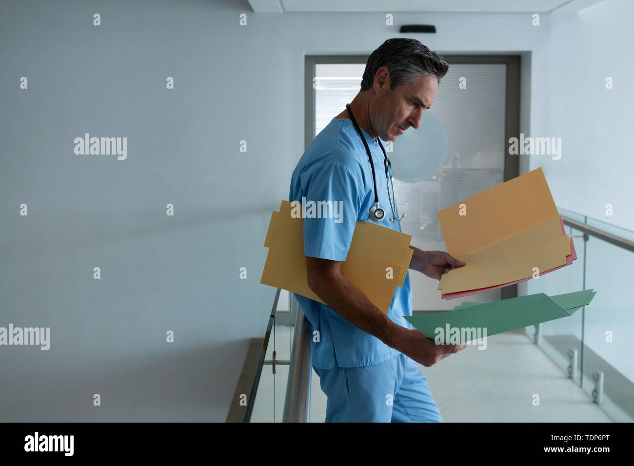 Male doctor looking medical report in the corridor Stock Photo - Alamy
