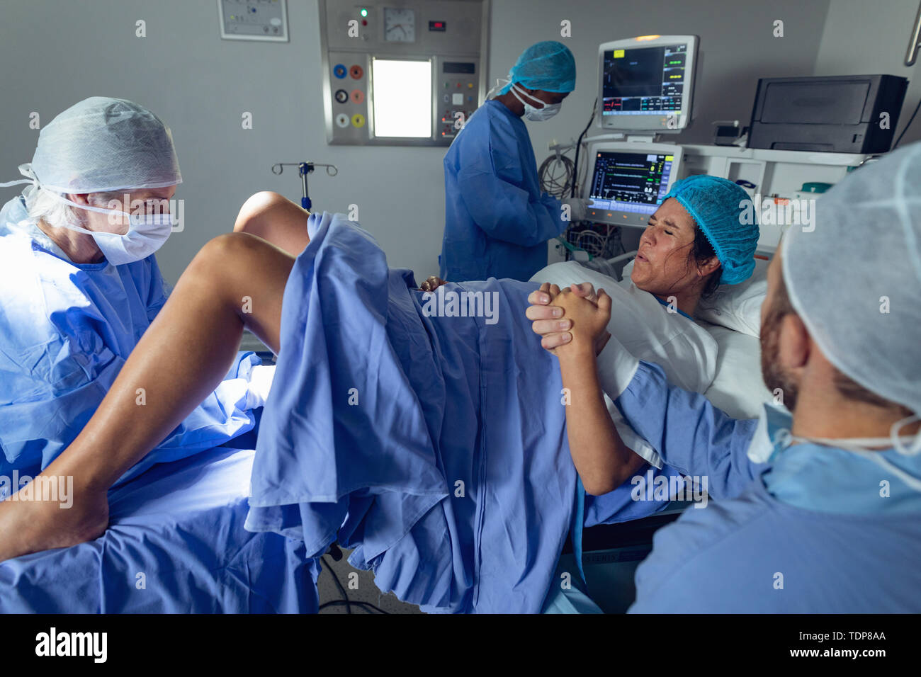 Surgeons examining pregnant woman during delivery while man holding her