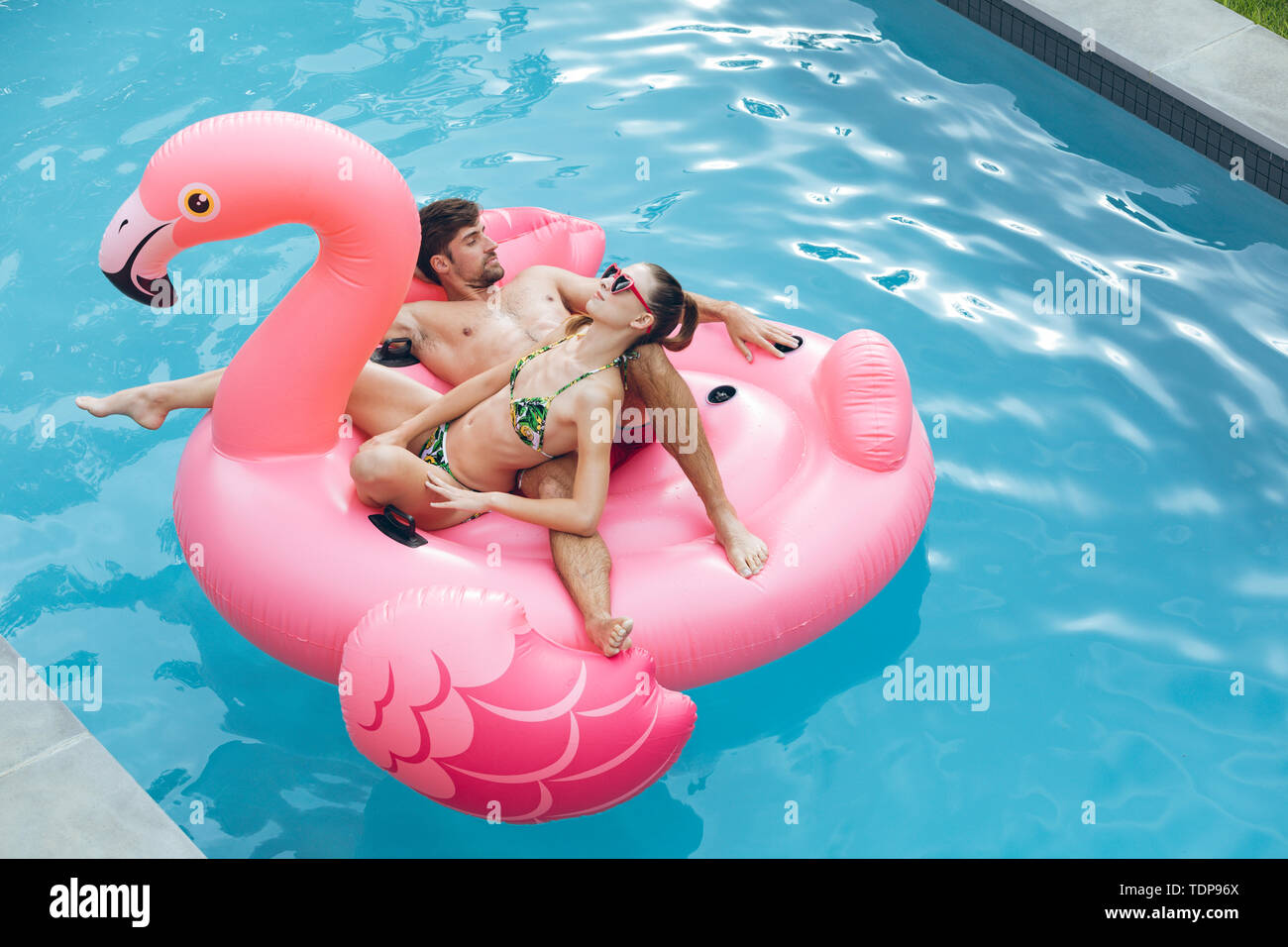 Couple sleeping together on a inflatable tube in swimming pool Stock Photo