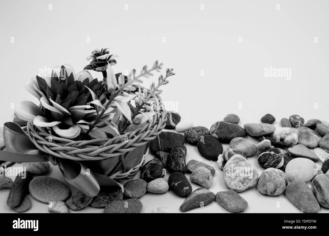 Small wicker basket with bow and flowers in black and white Stock Photo