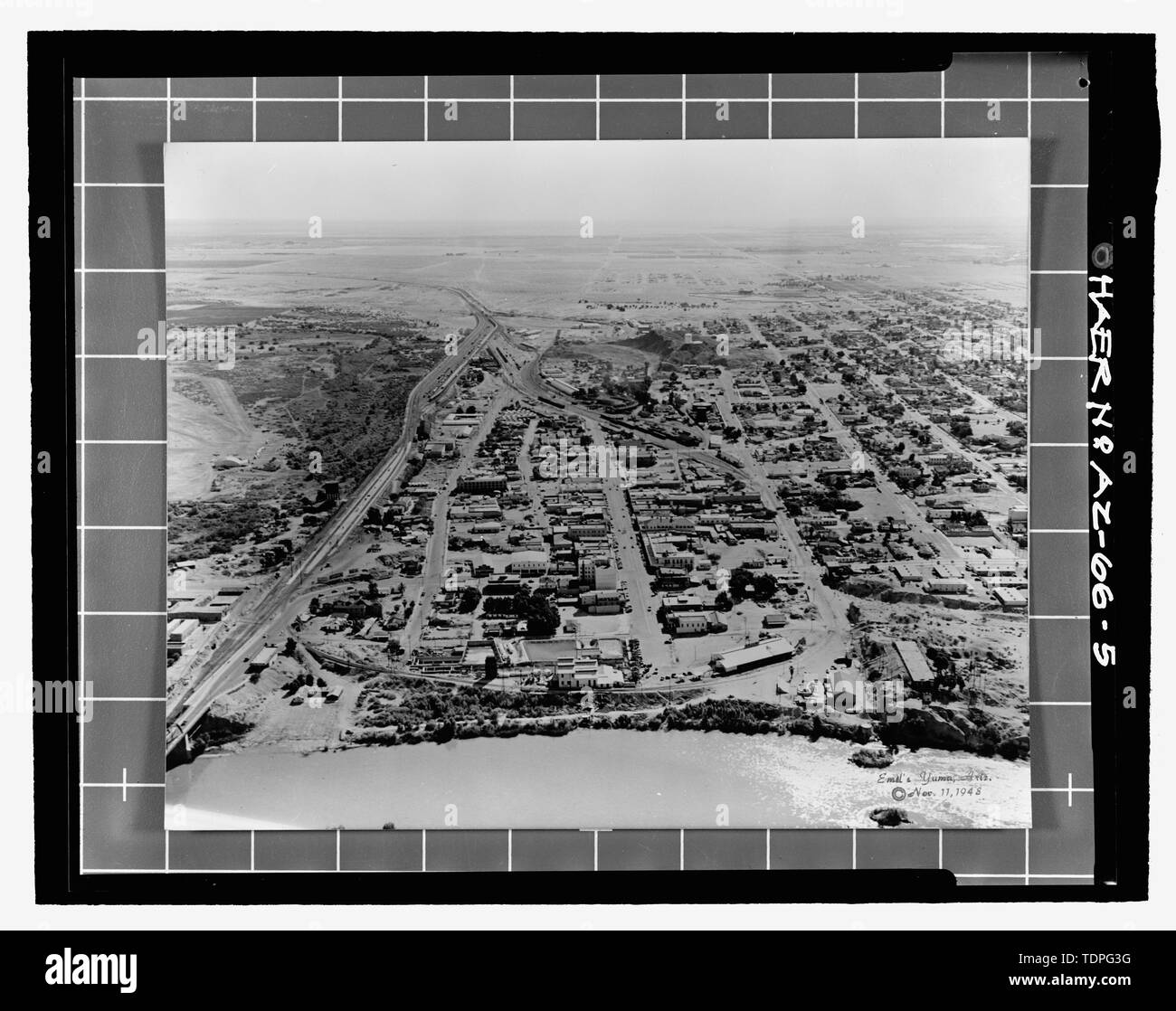 (original print in collection of Gerald A. Doyle, Phoenix) Emil Eger, Photographer, November 11, 1948.  AERIAL VIEW LOOKING SOUTH OF THE YUMA CROSSING. THE SPRR WATER SETTLING RESERVOIR IS ON THE HILLOCK AT THE BOTTOM RIGHT CORNER OF THE IMAGE. THE LOCATION OF THE SPRR BRIDGES AT MADISON AVENUE IS MARKED BY THE TWO PIERS IN THE RIVER. THE CIRCULAR FOUNDATION OF THE SWING SPAN IS ON THE SHORELINE IMMEDIATELY BEYOND THE SECOND PIER. THE RESERVOIR ROOF IS INTACT. - Southern Pacific Railroad Water Settling Reservoir, Yuma Crossing, south bank of Colorado River at foot of Madison Avenue, Yuma, Yuma Stock Photo