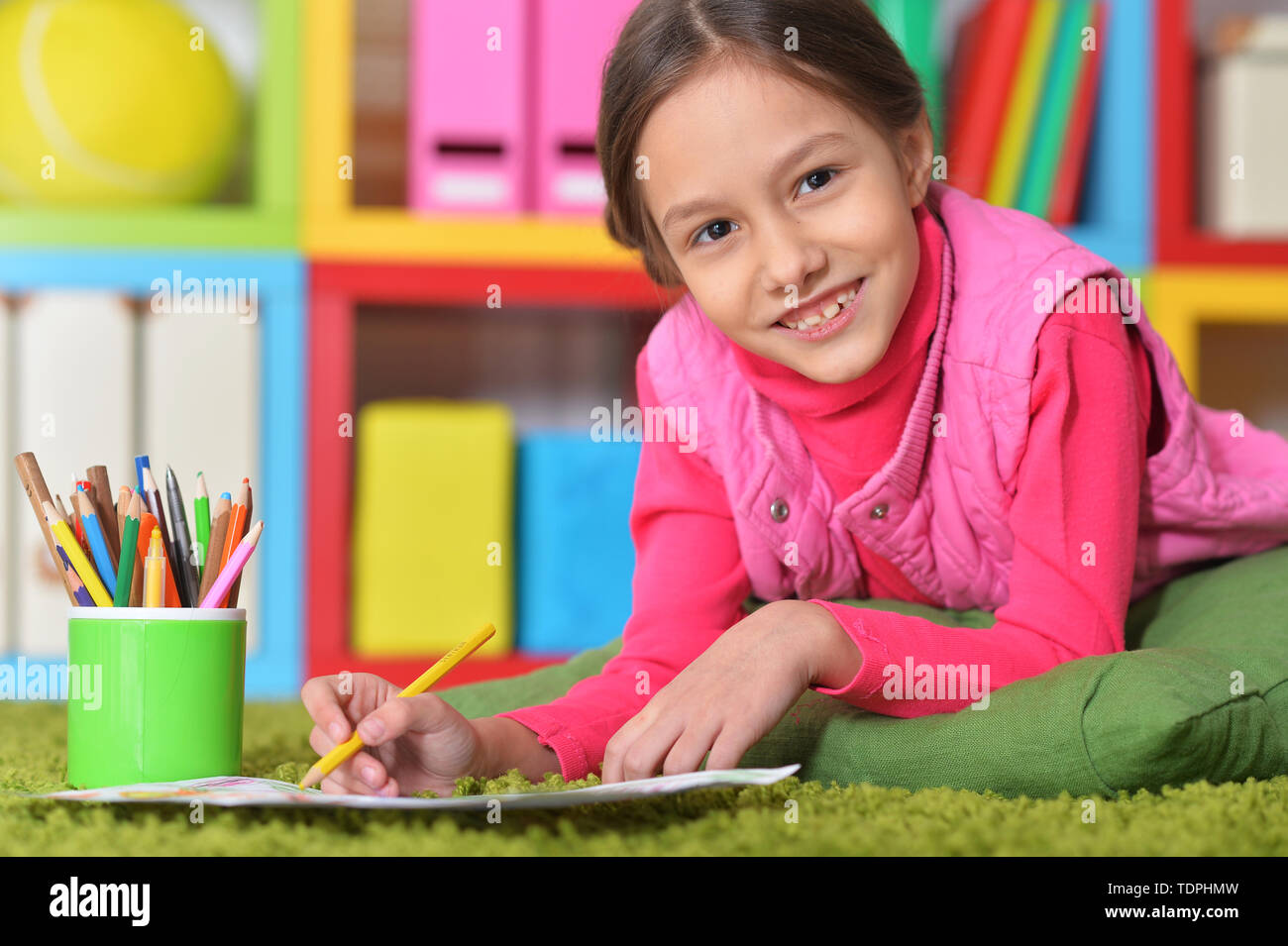 Cute little girl lying on floor and drawing Stock Photo - Alamy