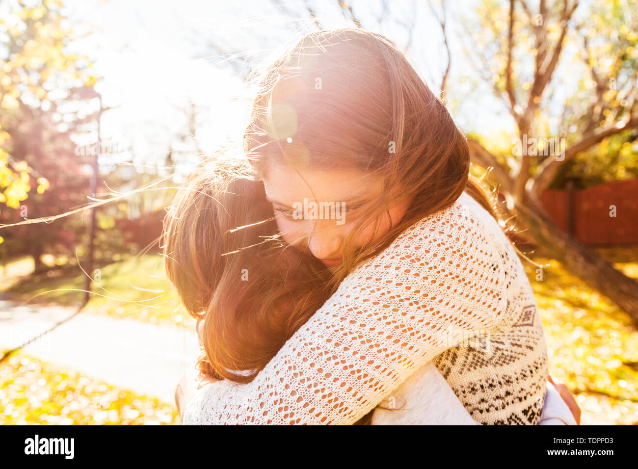 Two sisters hugging each other in a city park on a warm autumn day: Edmonton, Alberta, Canada Stock Photo