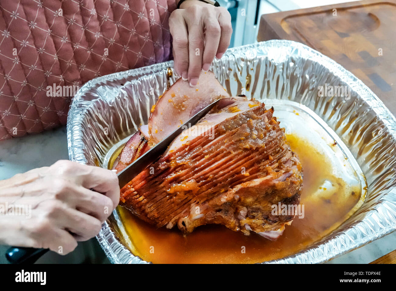 Miami Florida,Christmas winter holiday dinner,cooked,spiral cut ham,aluminum disposable roasting tray,knife,cutting,FL190104004 Stock Photo