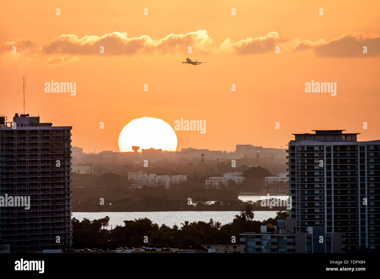 Miami Florida,Biscayne Bay,North Bay Village Island,sunset,city skyline,buildings,amber color sky,orb,jet aircraft commercial airliner,setting sun,FL1 Stock Photo