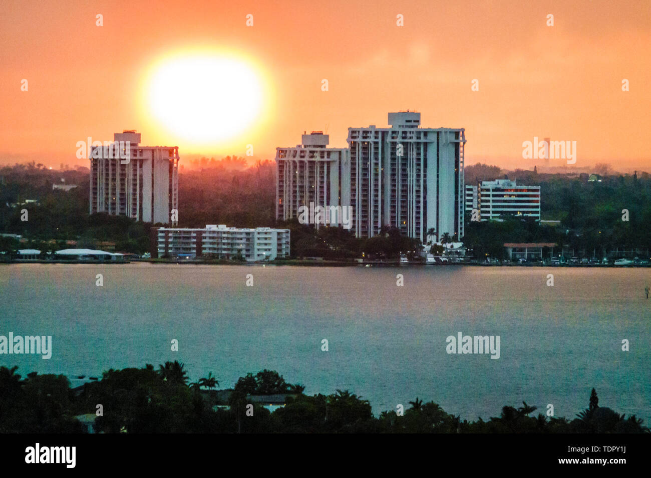 Miami Florida,Biscayne Bay sunset,city skyline,waterfront,residential buildings,hazy sky,setting sun,FL190505013 Stock Photo