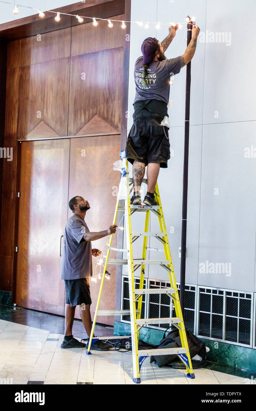 Orlando Florida,Museum of Art,inside interior,gallery galleries,worker safety,accidents,dangerous jobs,setting up,hanging lights,ladder,Black Blacks A Stock Photo