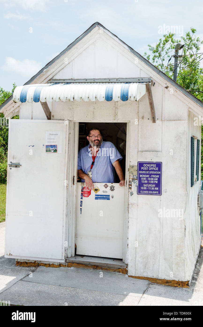 Florida,Ochopee,Everglades,Tamiami Trail,smallest post office,wood frame shed,post clerk,worker,man men male,service window,flag,FL190512075 Stock Photo