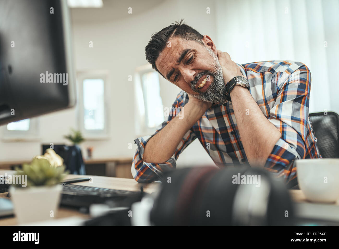 Mature handsome overworked businessman sitting in the office having