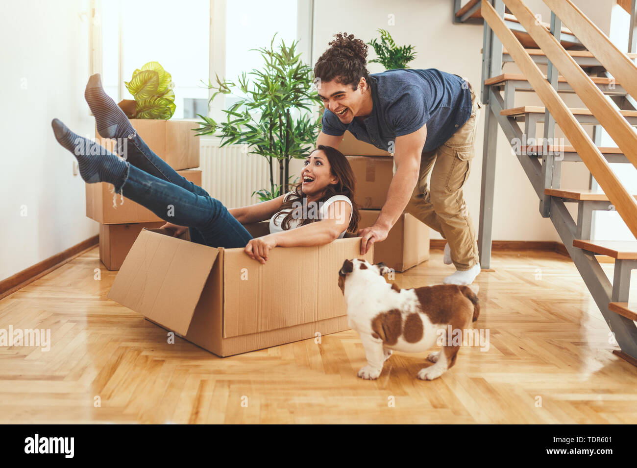 The young happy couple is moving into a new house. They are unpacking ...
