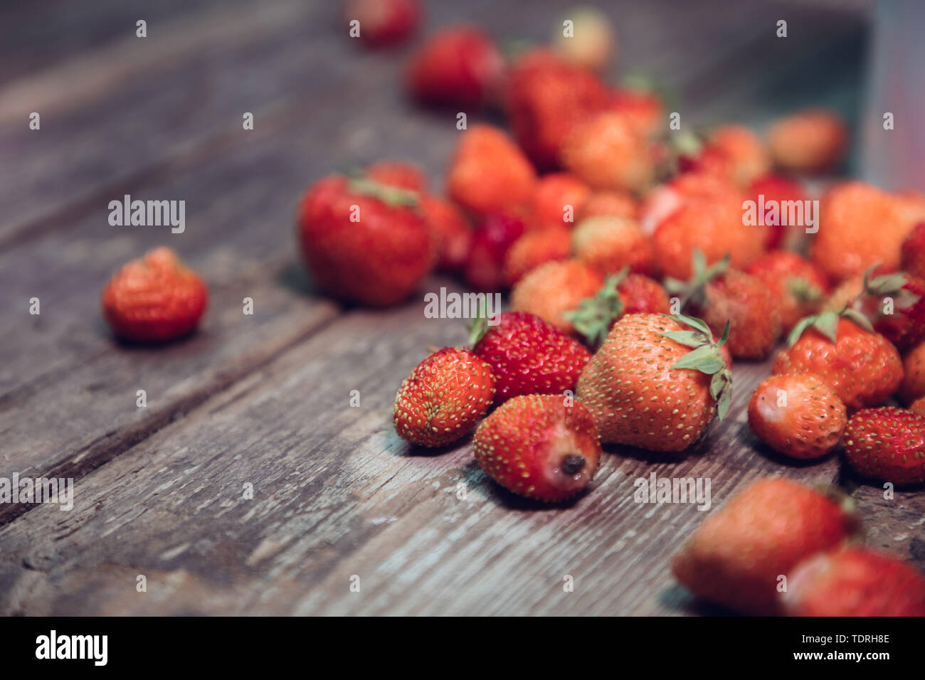strewn strawberries on an old wooden table Stock Photo - Alamy