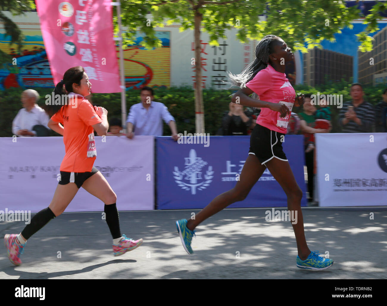 A Chinese runner is trying to catch up with African athletes in front of the women's marathon. Stock Photo