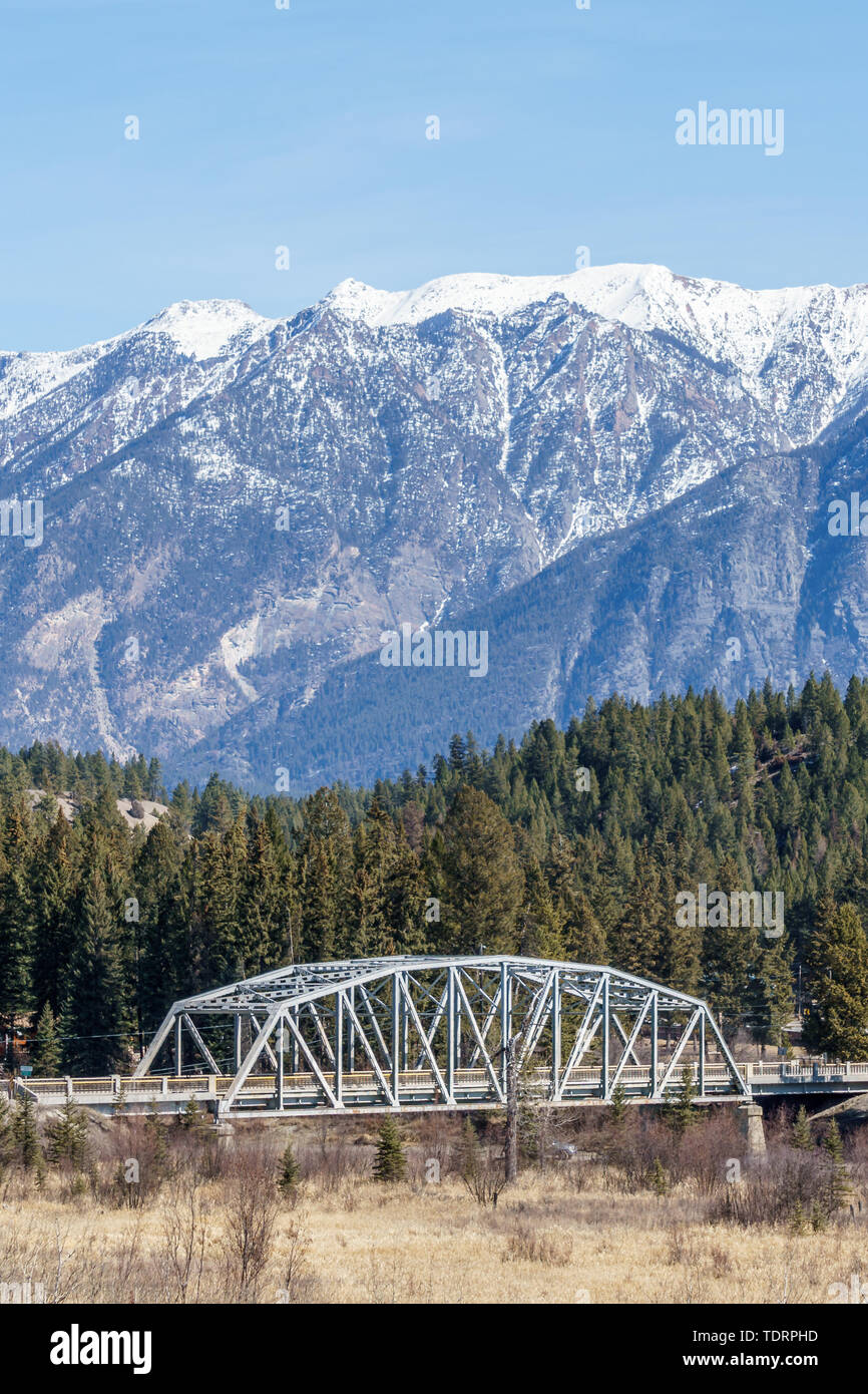 metal bridge over a river with mountain in snow in the background ...
