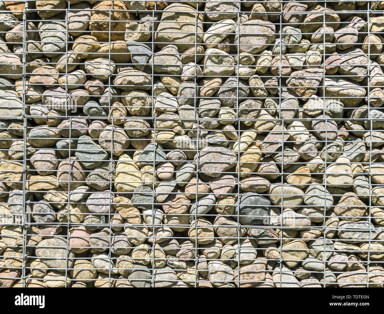 gabion wall pattern. metal grid with many round natural stones inside Stock  Photo - Alamy