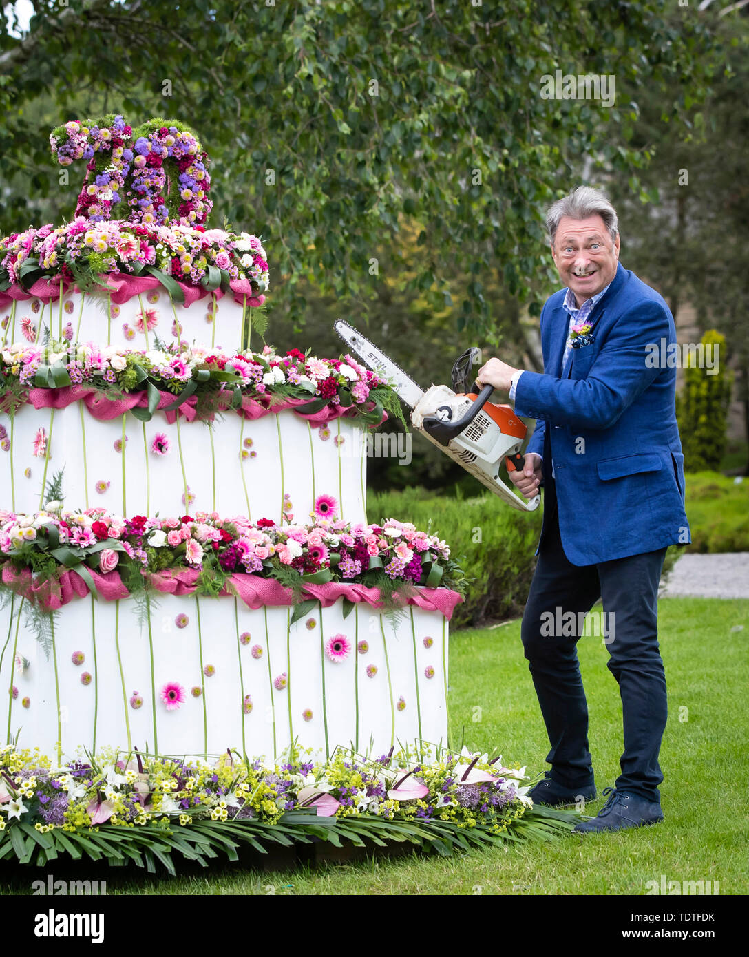 TV gardener Alan Titchmarsh pretends to cut giant three-tiered floral birthday cake with a chainsaw to mark 70 years of the RHS Garden Harlow Carr, during the RHS Garden Harlow Carr Flower