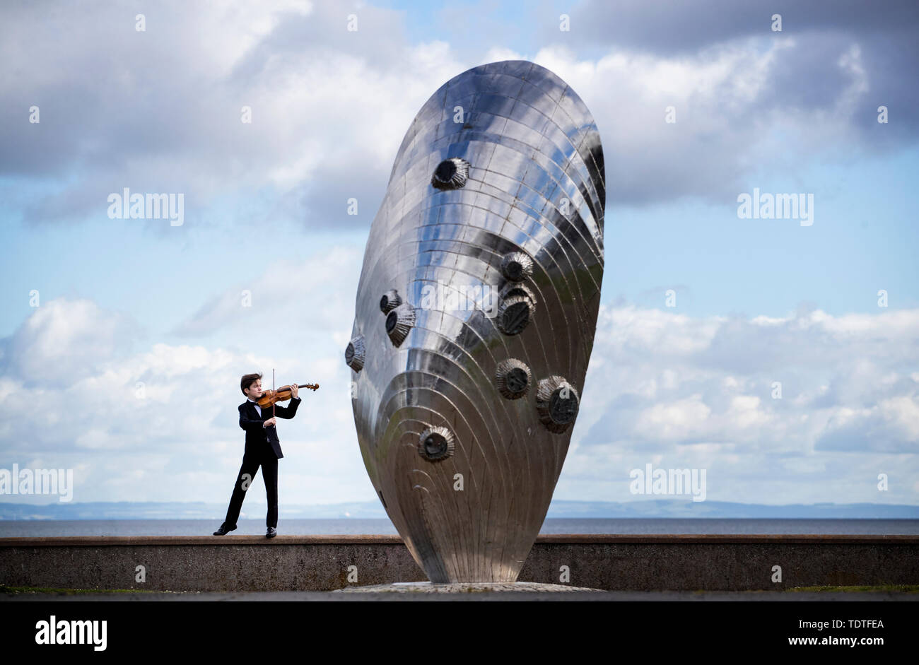 Viktor Seifert, 12, from St Mary's Music School in Edinburgh, plays the Orca Driftwood Viola alongside the giant mussel shell sculpture at Musselburgh, East Lothian, ahead of his performance at the Royal Academy of Music in London on July 18th 2019, in the 'Dance For The Sea' event which supports the work of the Marine Conservation Society. Stock Photo