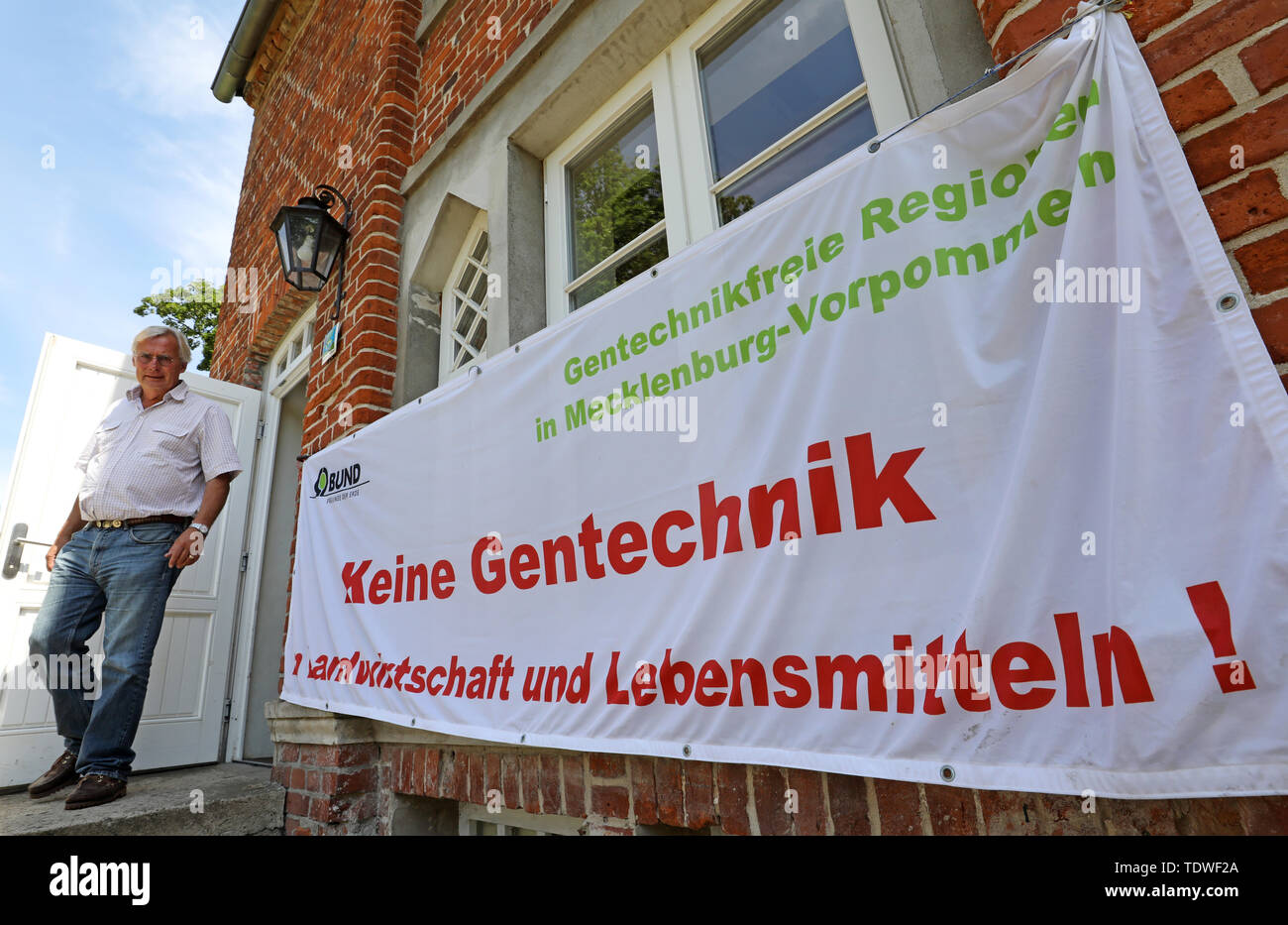 19 June 2019, Mecklenburg-Western Pomerania, Dalwitz: Heinrich von Bassewitz, initiator of the first GMO-free region in Germany, passes a banner with the inscription 'No genetic engineering in agriculture and food' at the 14th Land Meeting of GMO-free Regions in Mecklenburg-Western Pomerania. This time, the meeting will focus in particular on the risks of the new genetic engineering processes, but also on better networking and possible actions by the regions. In and around Dalwitz, Germany's first GMO-free region was created in 2003 from a total of 15 farms. Photo: Bernd Wüstneck/dpa-Zentralbi Stock Photo