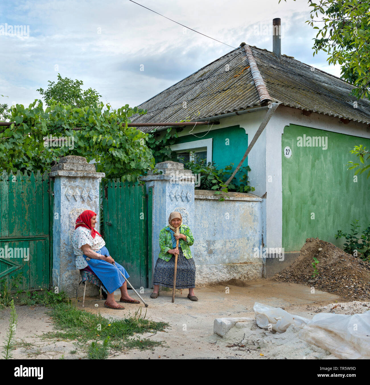 two old countrywomen sitting at the garden gate and tattling, Moldova Stock Photo