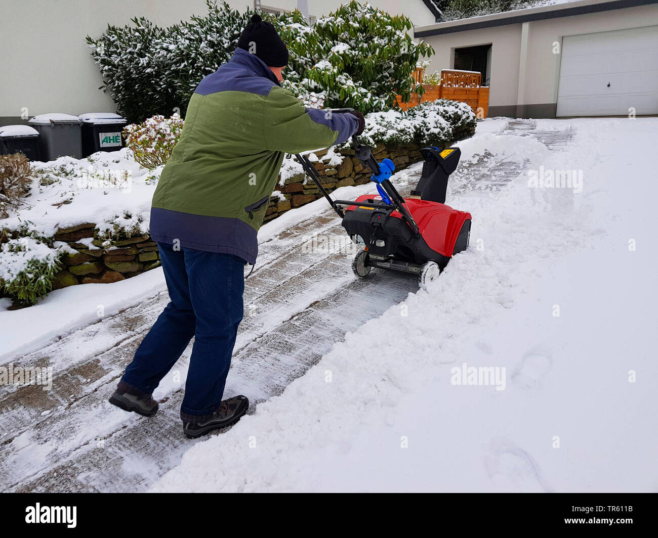 man with snowblow removing snow from a pavement, Germany, North Rhine-Westphalia, Ruhr Area, Witten Stock Photo