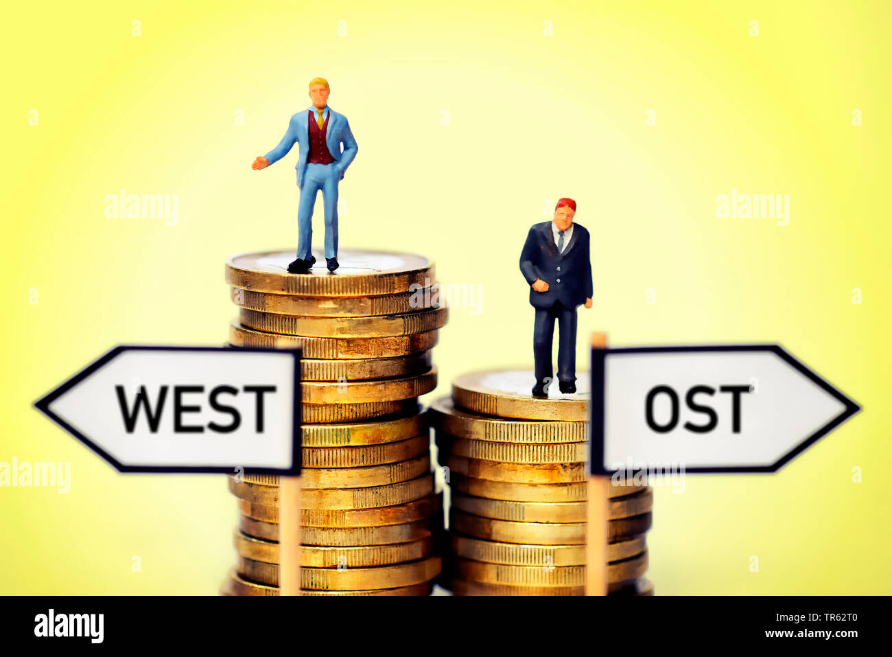 Businessmen On Coin Piles Symbolizing The Unequal Wages Between