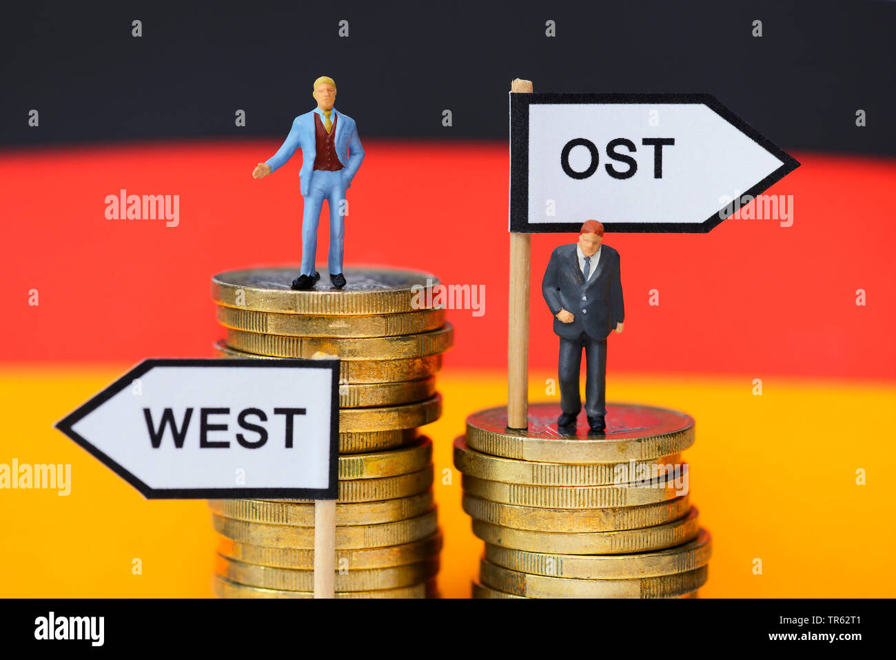 Businessmen On Coin Piles Symbolizing The Unequal Wages Between