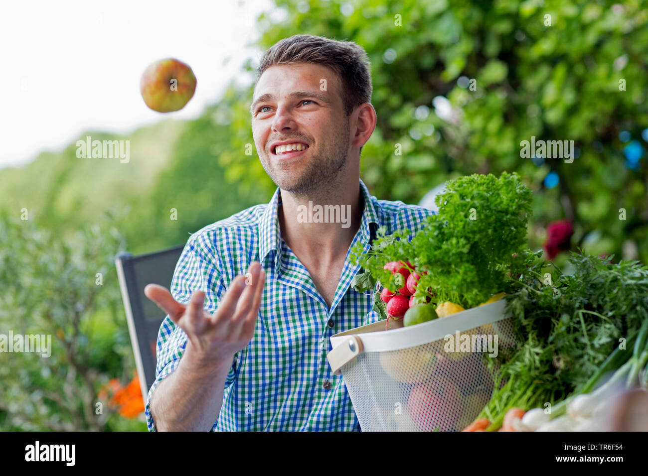 young man throwing up an apple, Germany Stock Photo