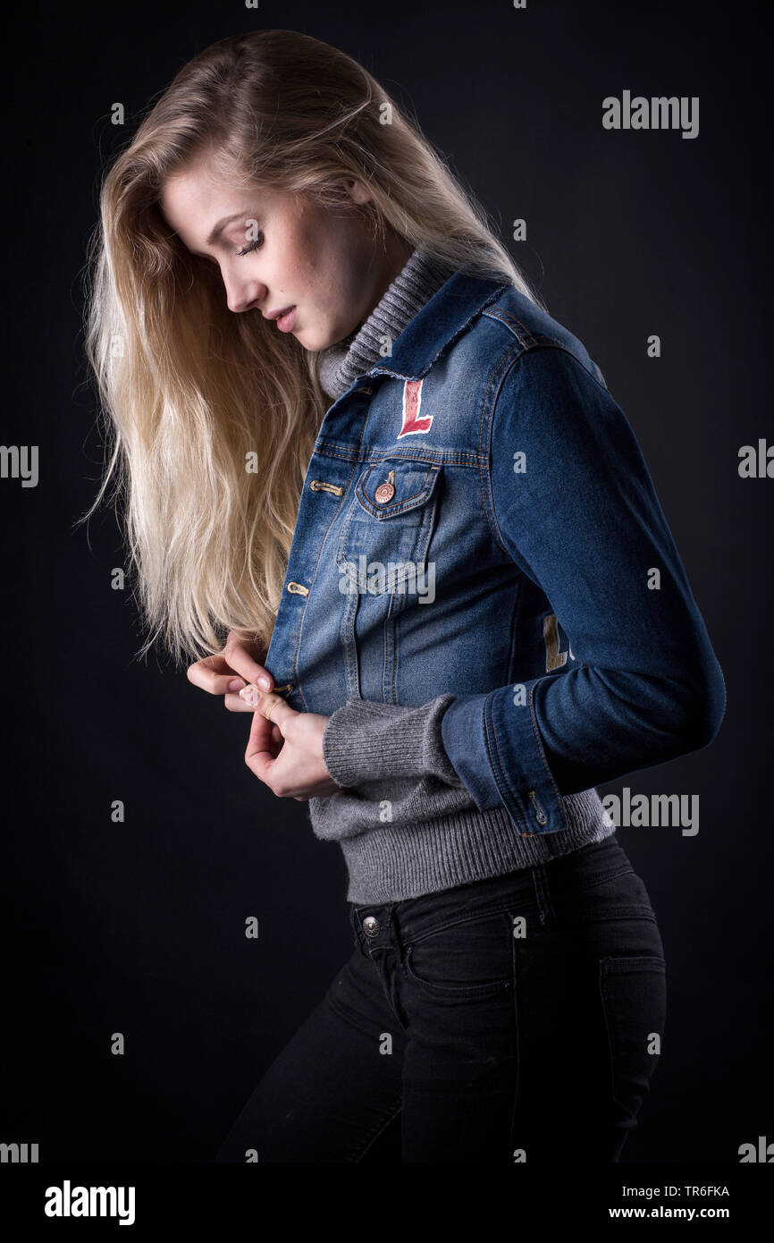 young blond woman fastening up her jacket, side view, Germany Stock Photo