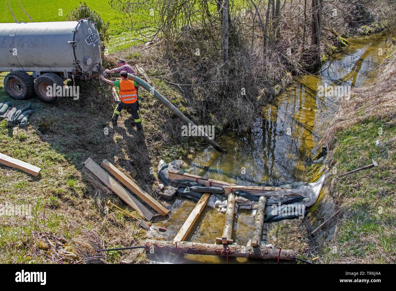 firefighter building a barrier in a creek after illegal discharge of manure, Germany, Bavaria Stock Photo