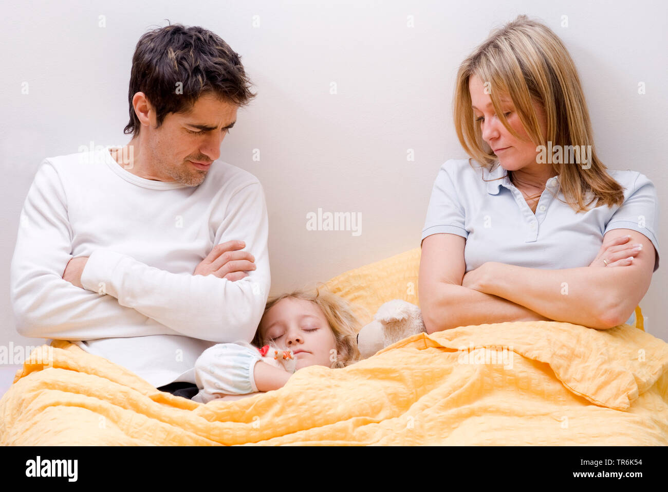 daughter sleeping between parents in bed Stock Photo