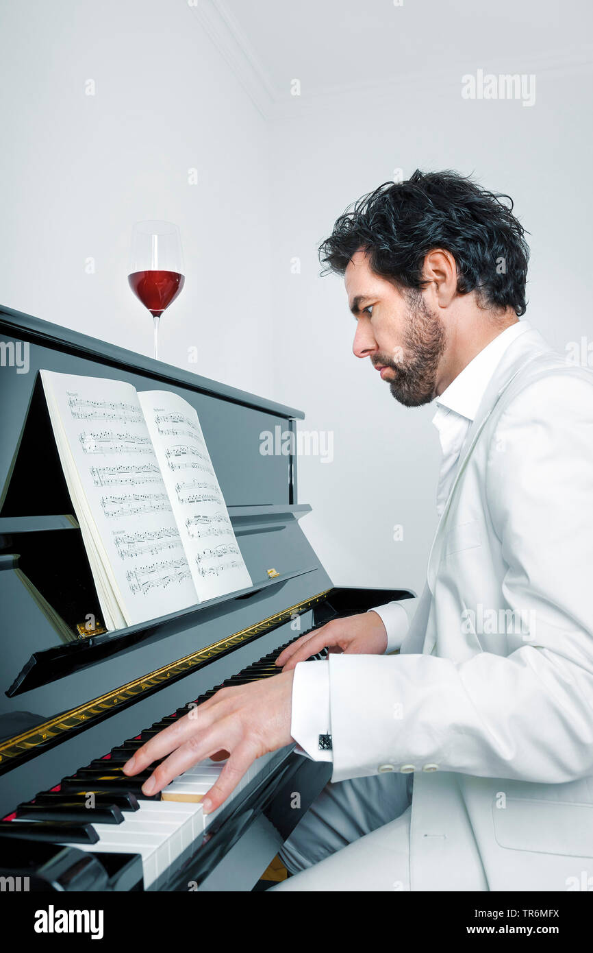 young man in white suit at a piano, Germany Stock Photo