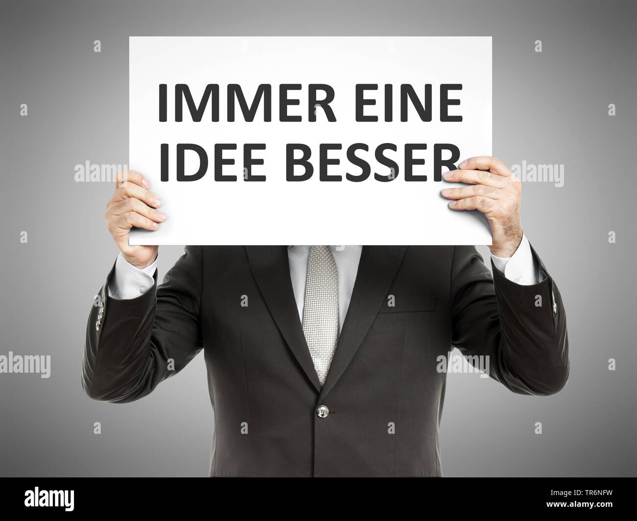 businessman holding a sign with the inscription Immer eine Idee besser, Always on Step ahead, Germany Stock Photo
