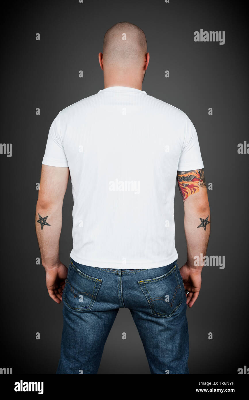 young tattooed man in t-shirt and jeans, rear view, Germany Stock Photo