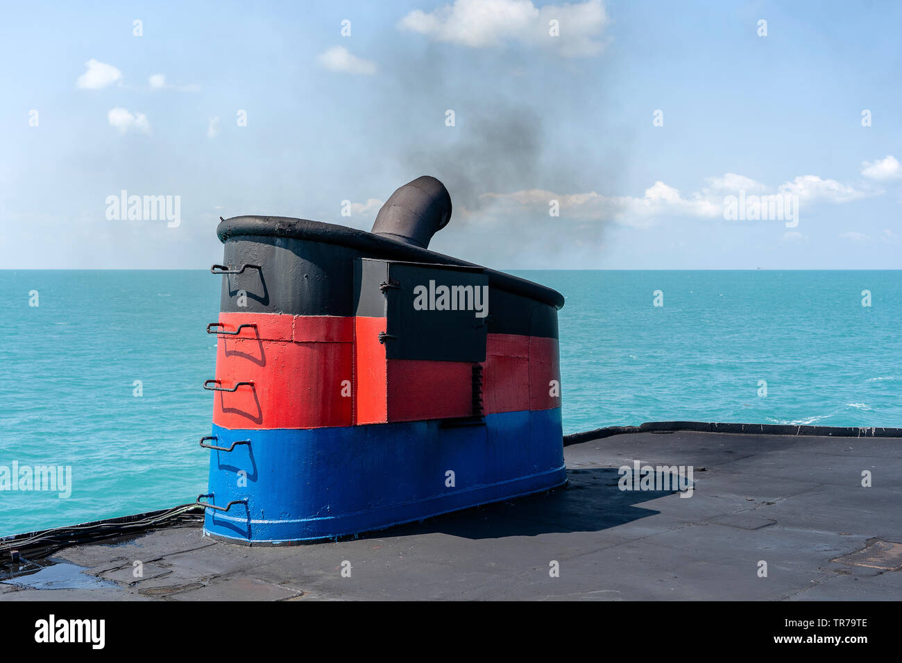 Smoke from ferry boat flue during sea with sunlight, sea water and blue