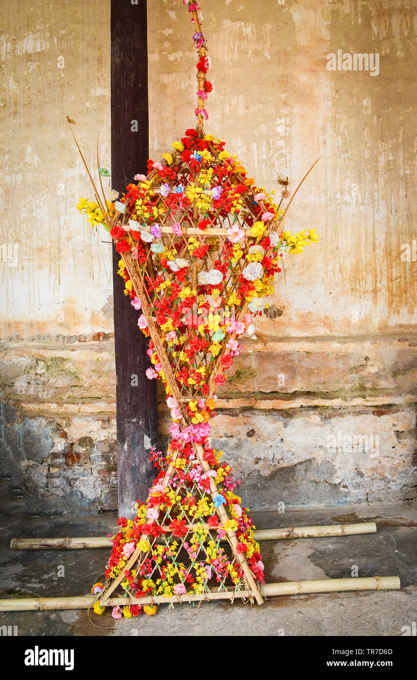 Colorful of flower decorate on bamboo tower shape pyramit with flowers on old wall for buddhist festival at Na Haeo Loei Thailand - naheaw Stock Photo