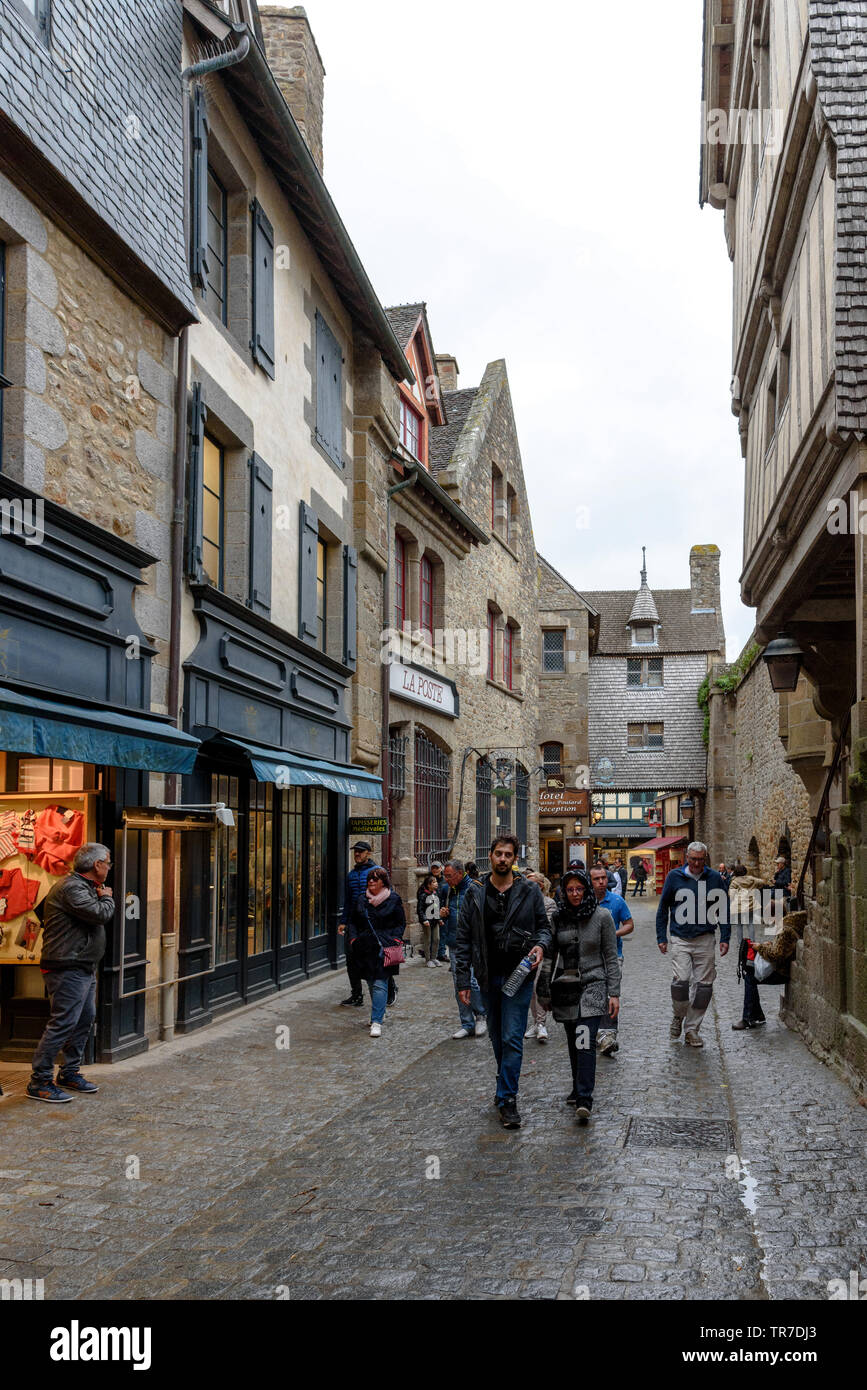 Tourists walking on the Grand Rue of Mont Saint-Michel on a rainy day Stock Photo