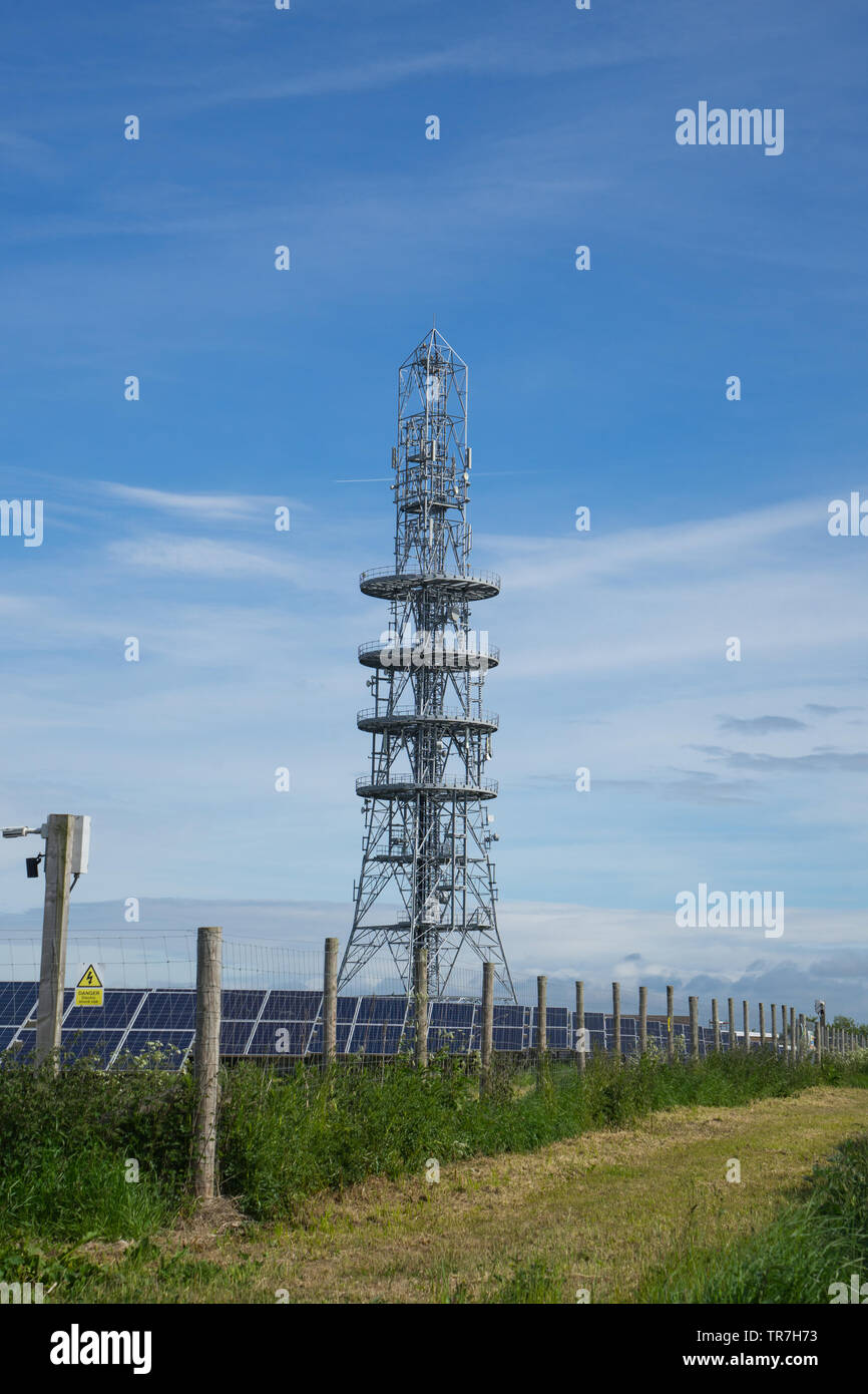 Mobile telephone communications tower next to a solar farm Stock Photo