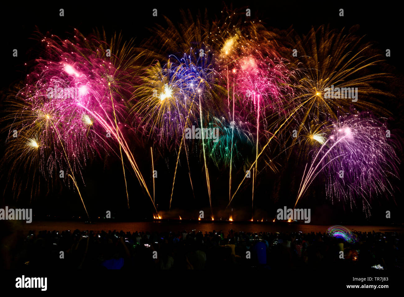 Colorful fireworks celebration and the night sky background with crowded people on the beach. Stock Photo