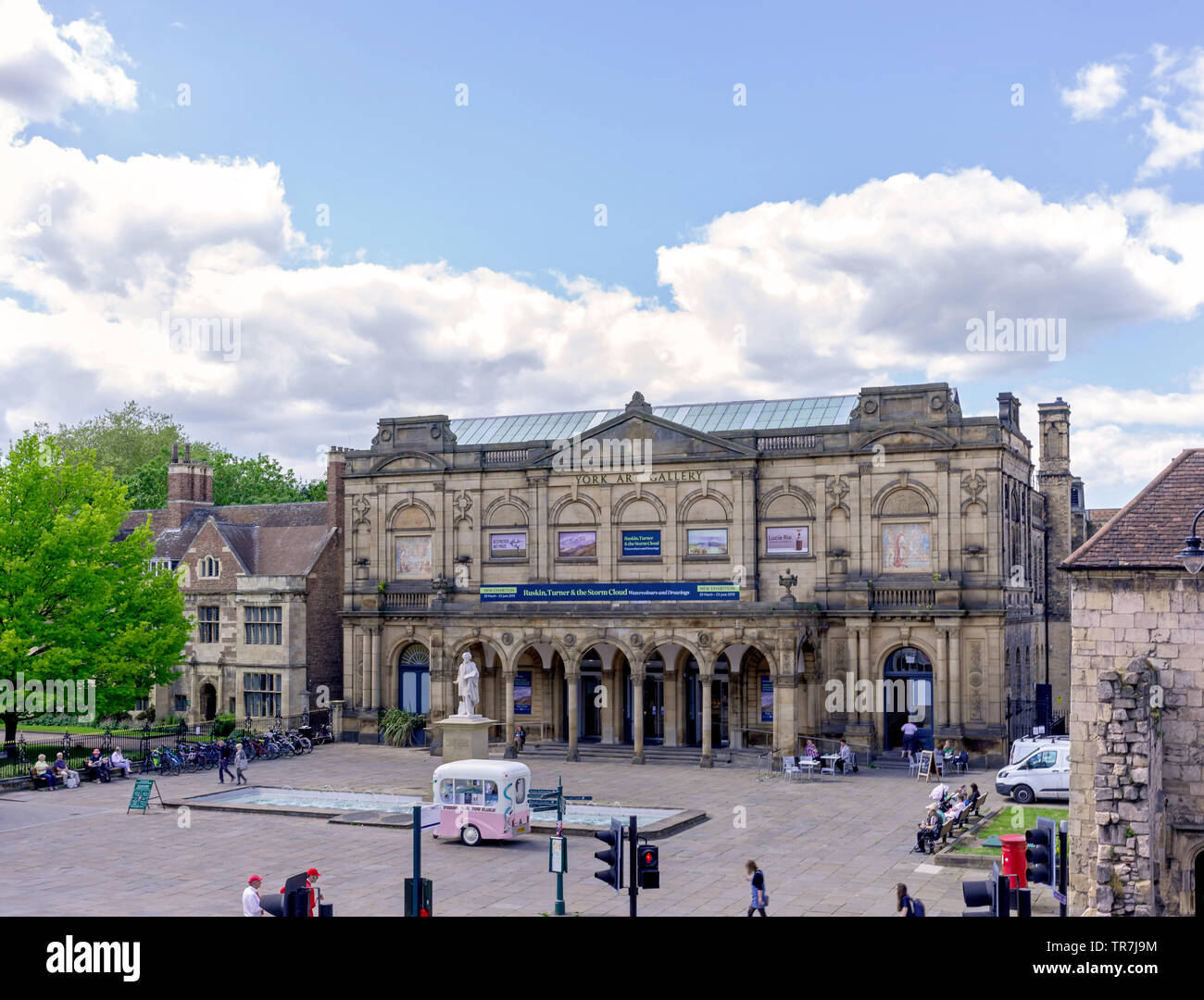 York Art Gallery.  A view of the gallery with a fountain and statue.  An ice-cream vendor is outside and people are sitting around the plaza. A blue, Stock Photo