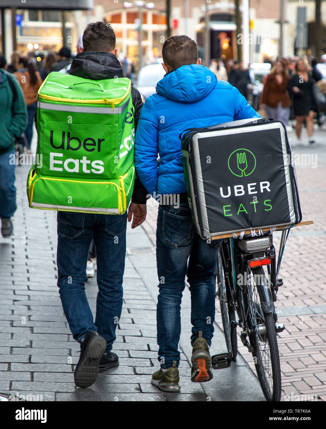 Amsterdam, Netherlands, couriers of the food online delivery service Uber Eats, bicycle supplier and delivery courier on foot, Stock Photo