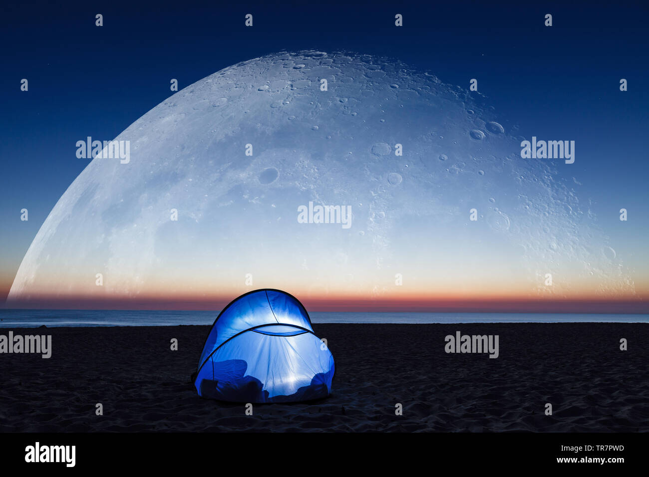 Amazing super big moon over the sea, beach and lit tent at sunrise Stock Photo