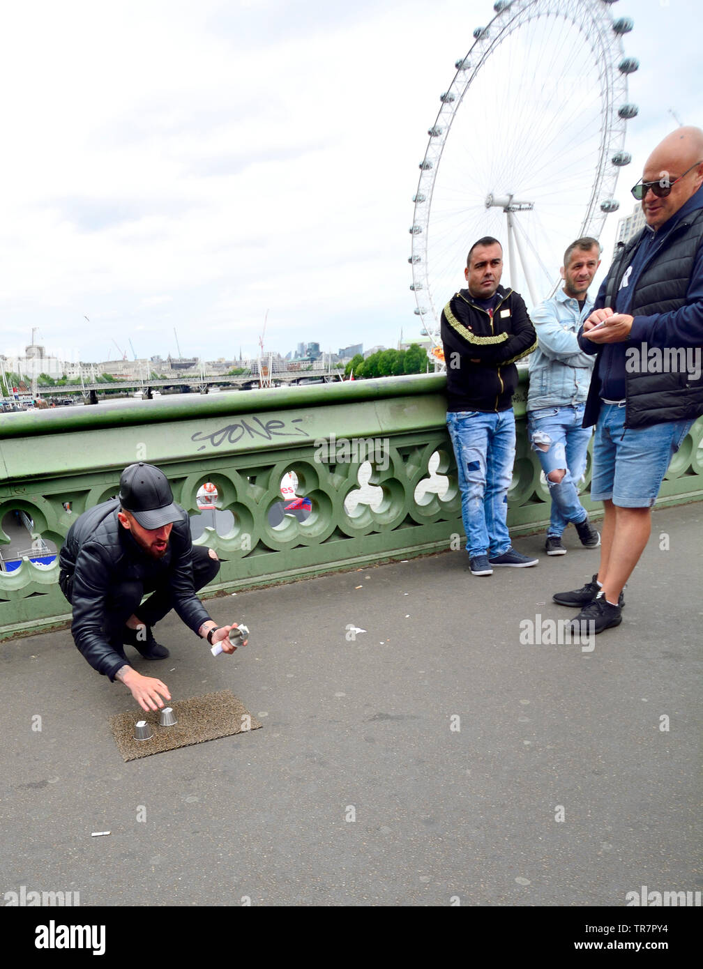 London, England, UK. Illegal Cup and Ball / 3 Cups Trick on Westminster Bridge, trying to con money from passing tourists Stock Photo