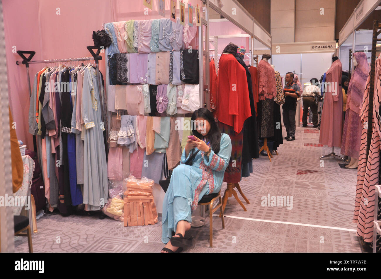 A booth keeper checks her phone at Indonesia Moslem Fashion Expo. Muslim fashion Industry grows very fast in Indonesia in the past several years. As c Stock Photo