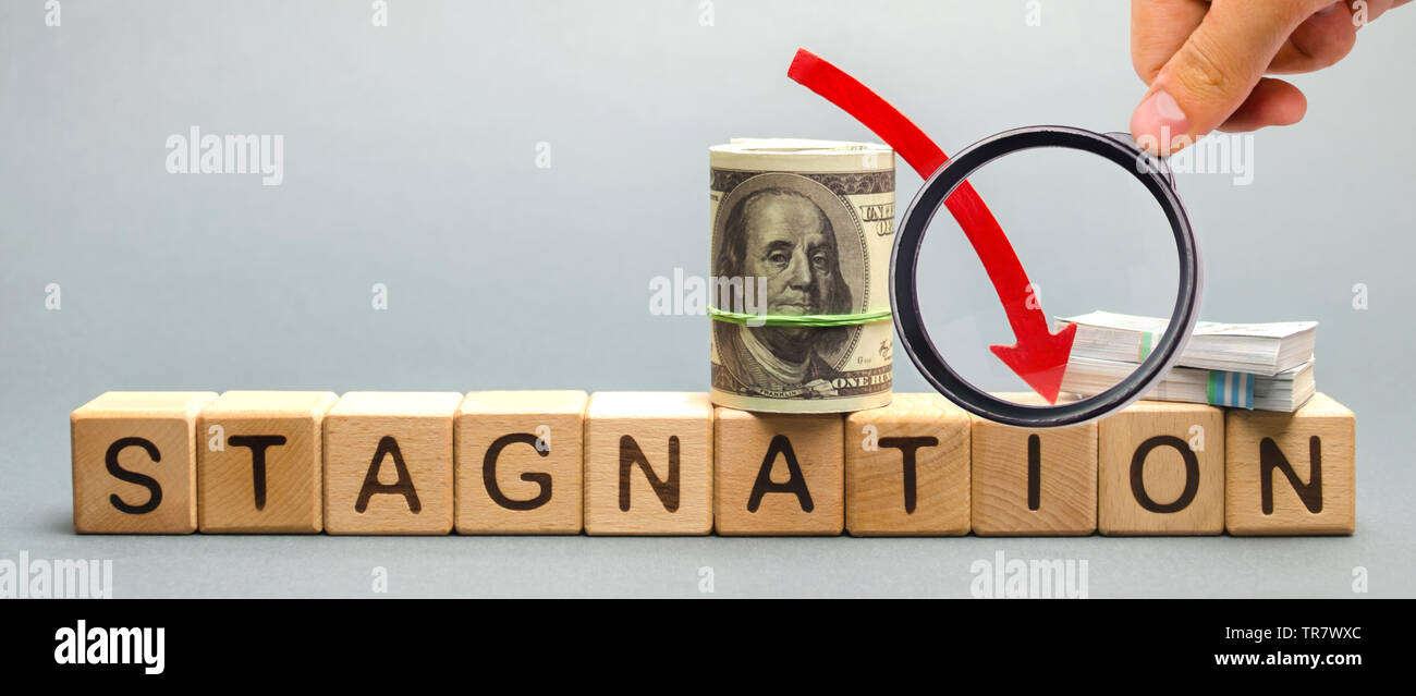 Wooden blocks with the word Stagnation and dollars. Prolonged period of slow economic growth, measured in terms of GDP growth. High unemployment. Econ Stock Photo