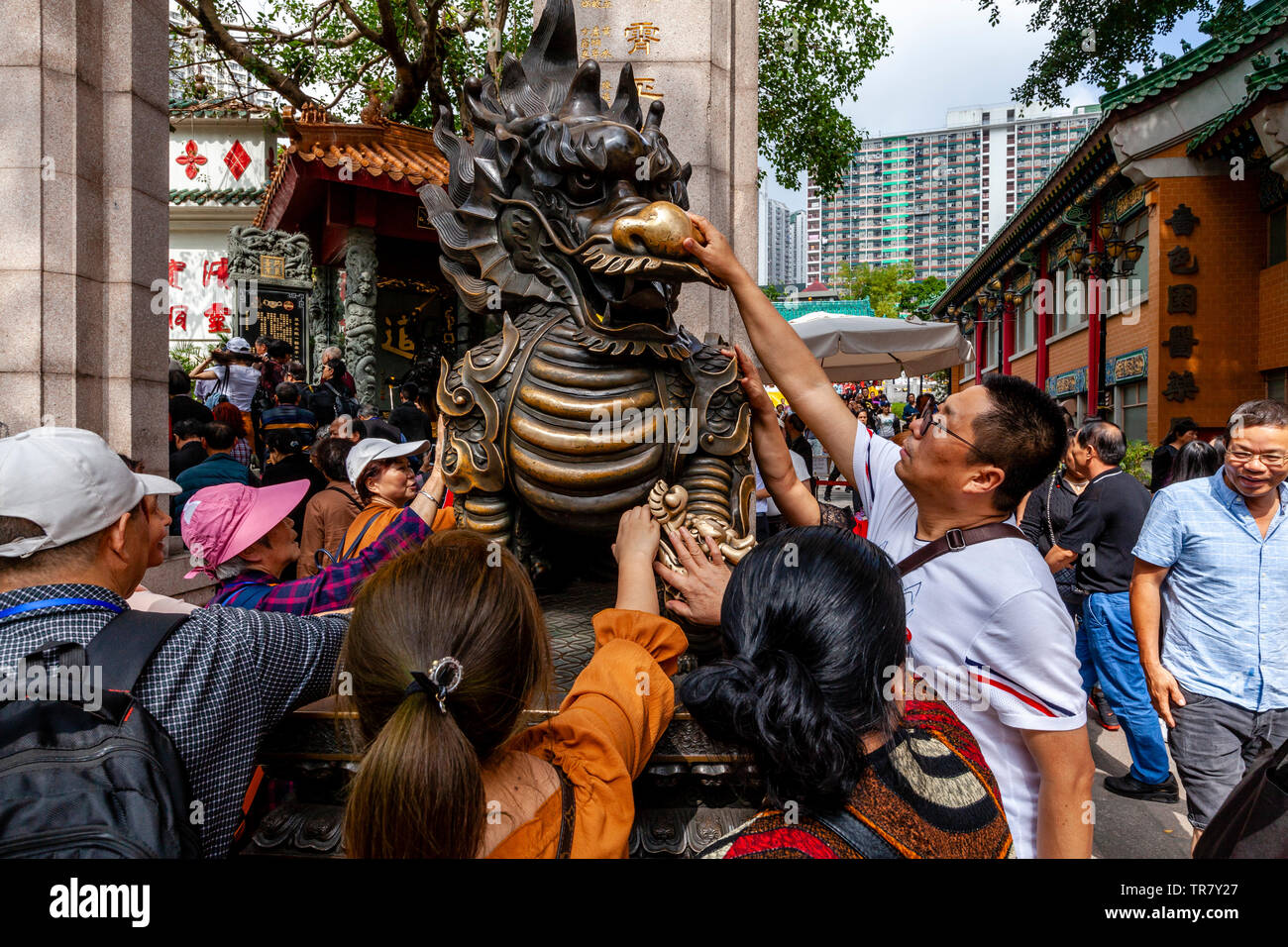 Chinese Tourists Rub The Dragon Statue For Good Luck At The Entrance To Wong Tai Sin Temple, Hong Kong, China Stock Photo
